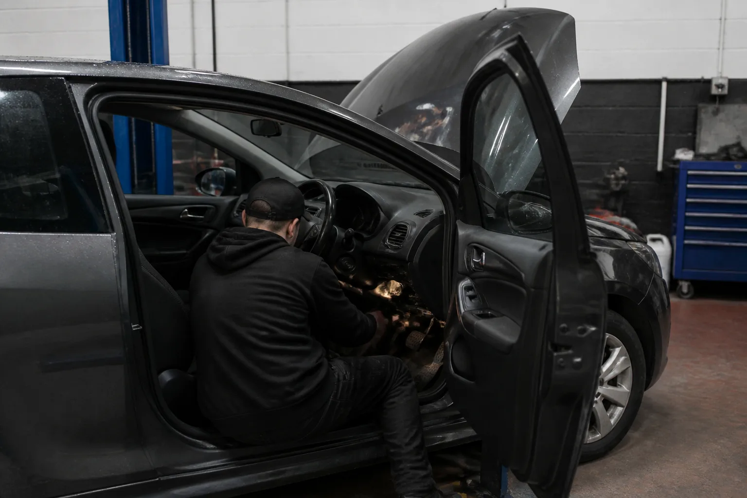 Mechanic inspecting the brake servo area of a hatchback in an independent UK garage