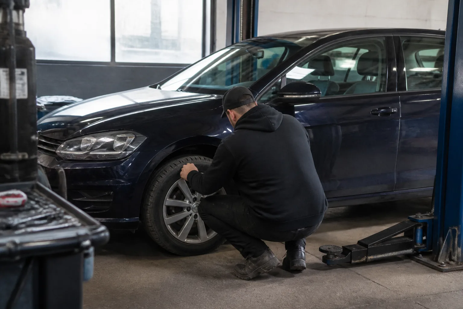 Mechanic inspecting the front wheel and steering area of a car in an independent UK garage