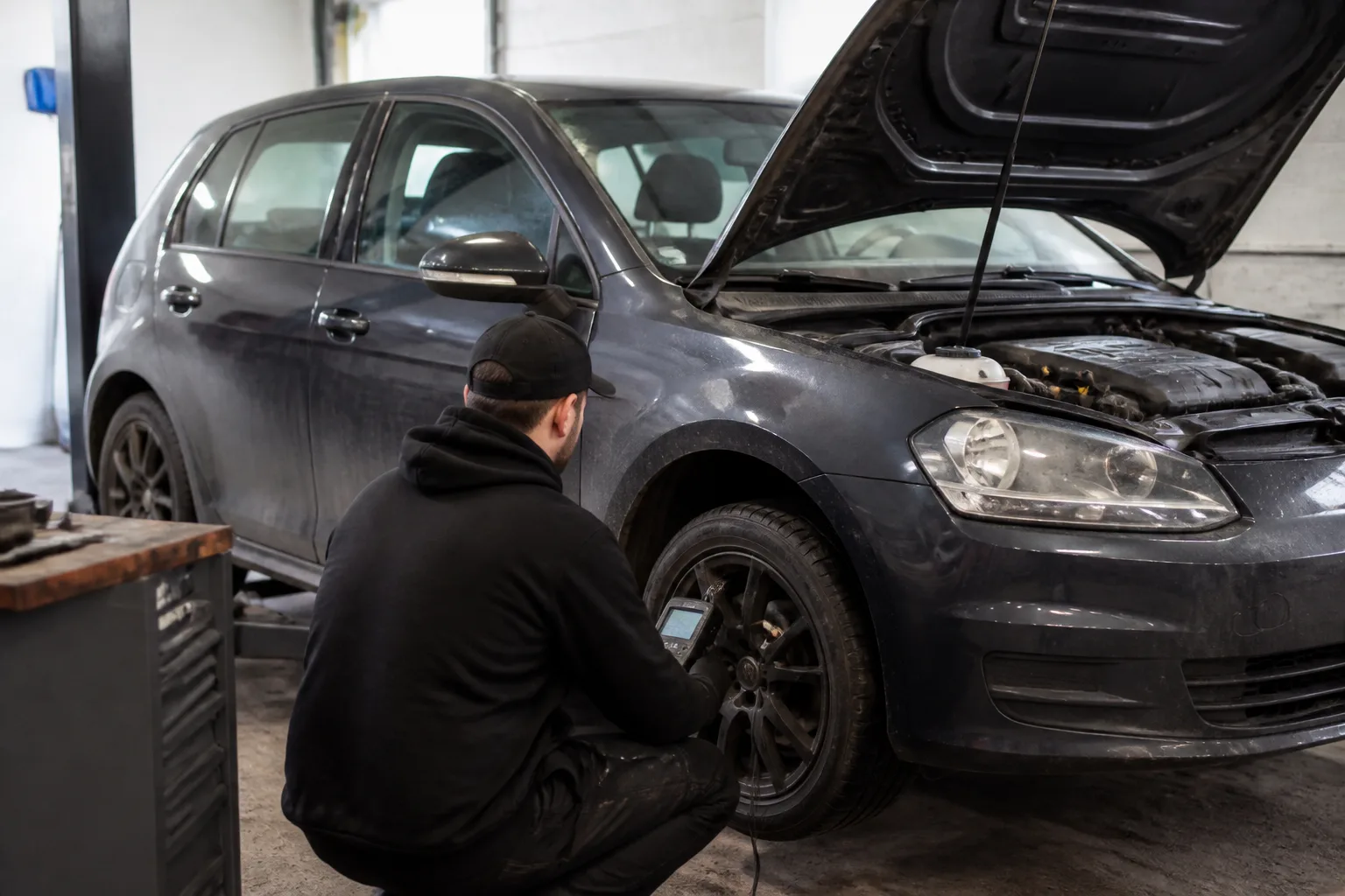 Mechanic using diagnostic equipment to investigate a traction control warning on a car in an independent UK garage