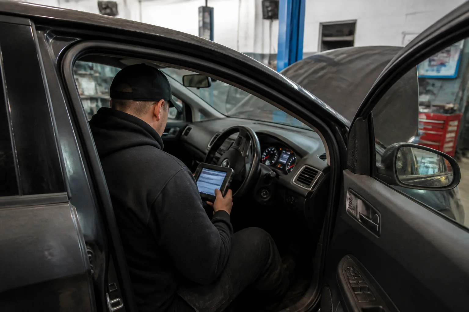 Mechanic using a diagnostic scanner to investigate an intermittent dashboard warning light in a UK garage