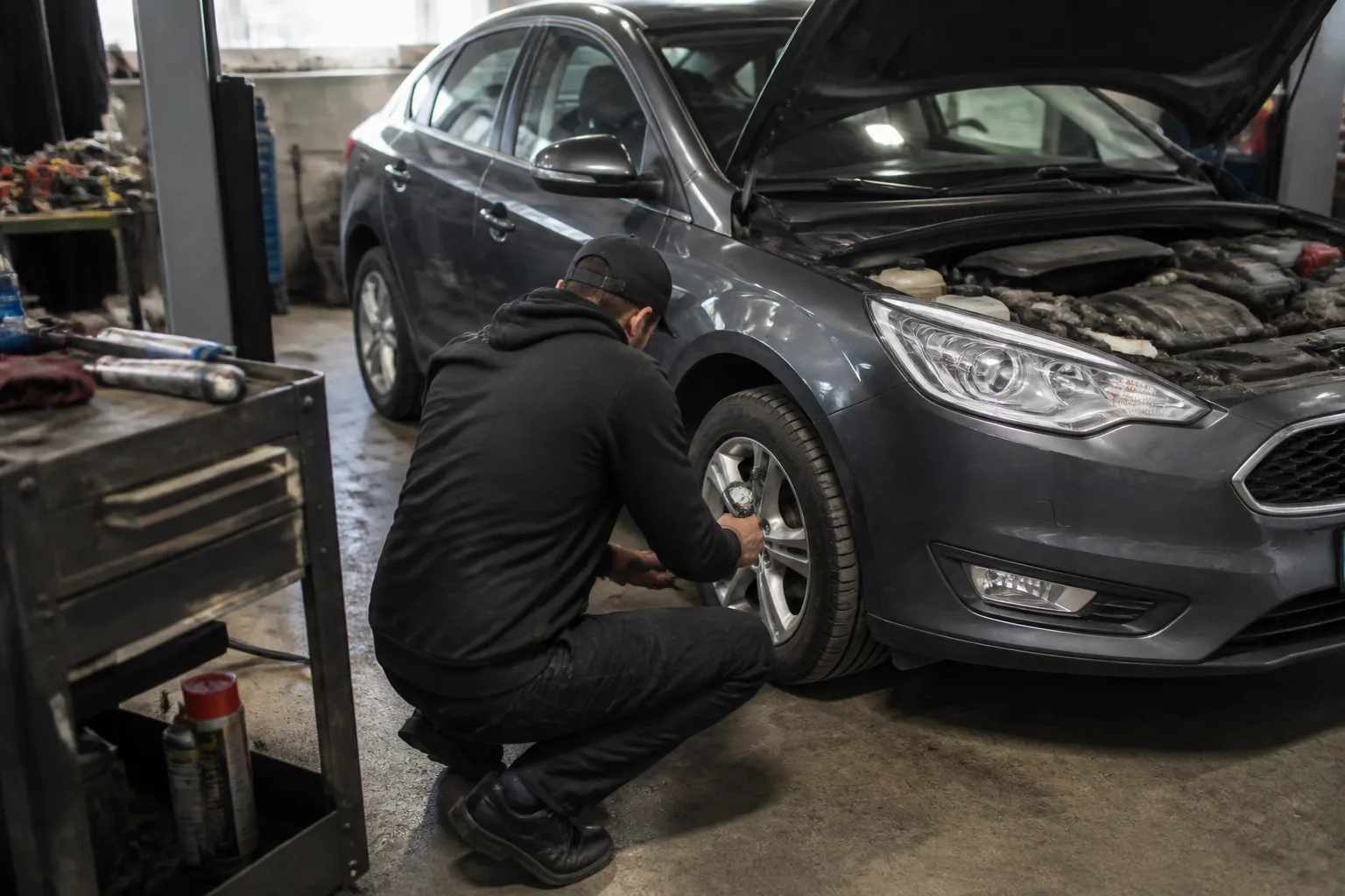 Mechanic checking a family car as part of a summer maintenance inspection in a UK garage